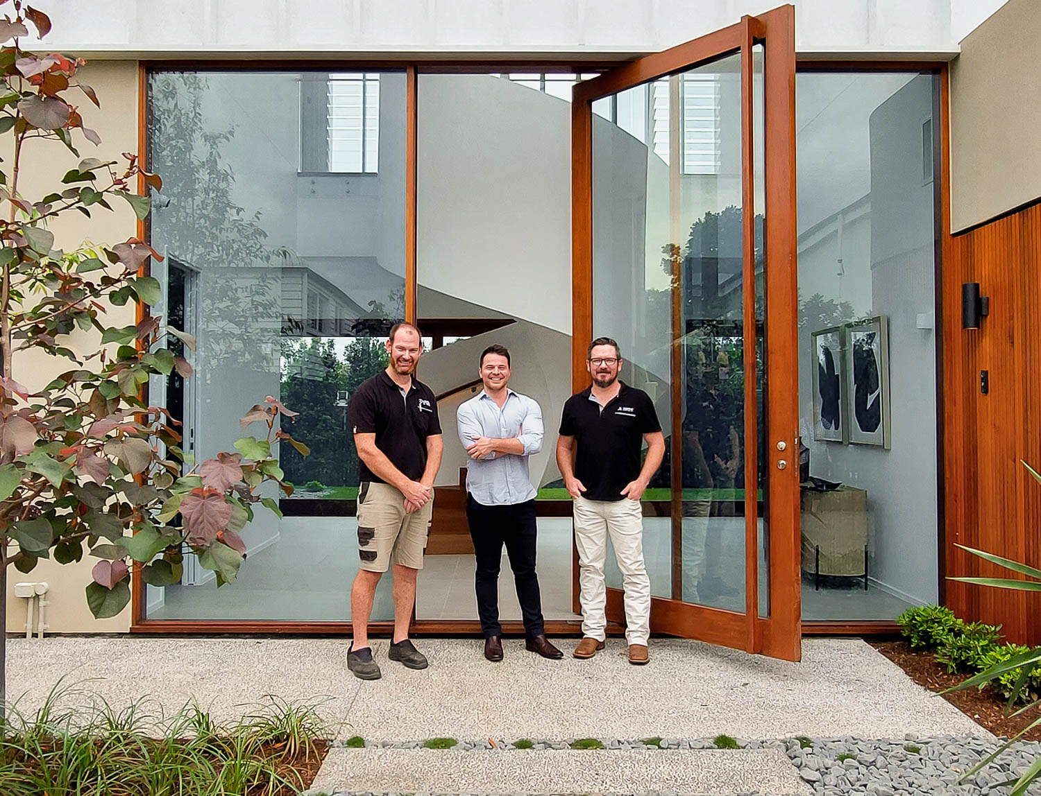 Allkind Joinery team photo behind large single lite pivot door glass